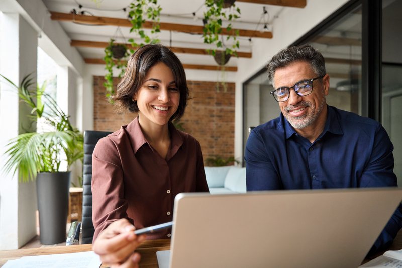 Two professionals reviewing work together on a laptop.